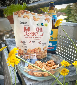 Tüte Chilli Cashews aus dem Weltladen. Davor eine kleine Glasschüssel mit den Cashewkernen